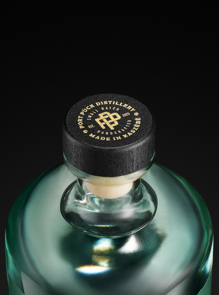 Elegancka butelka rzemieślniczej Okowity z Pigwowca Japońskiego z Port Puck Distillery, zbliżenie na czarną zakrętkę z logo Made in Kaszëbë.
