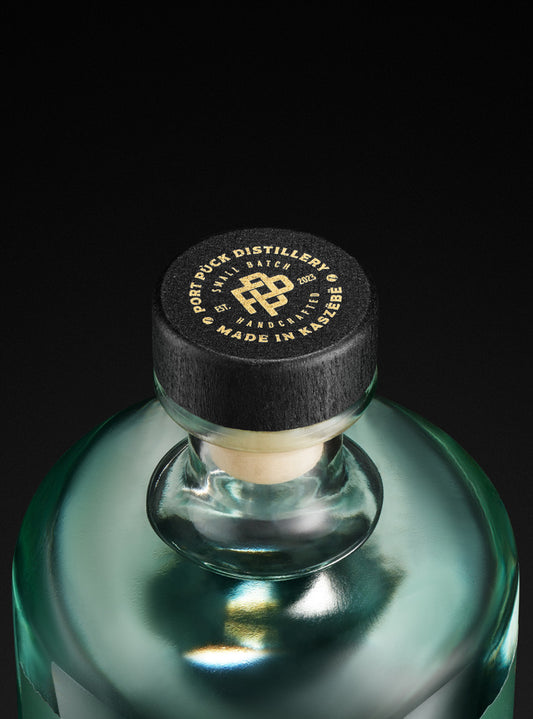 Elegancka butelka rzemieślniczej Okowity z Pigwowca Japońskiego z Port Puck Distillery, zbliżenie na czarną zakrętkę z logo Made in Kaszëbë.