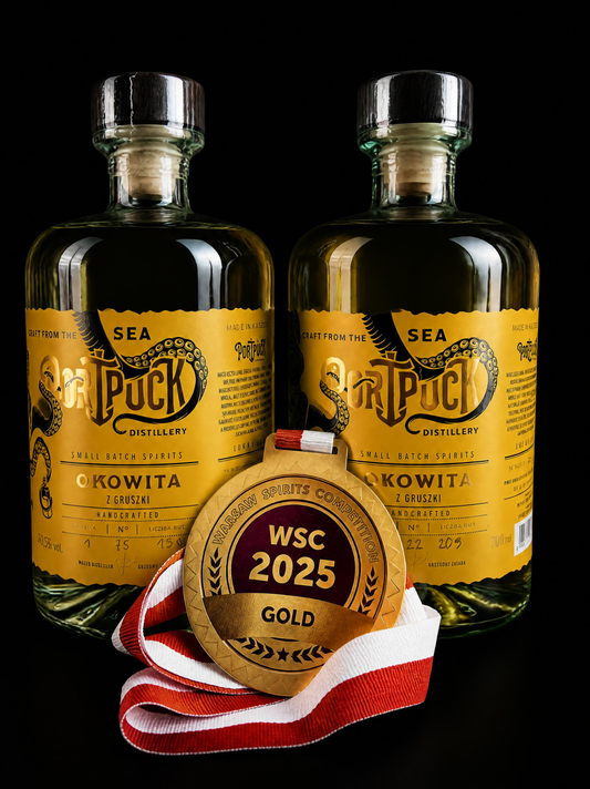 Złoty medal Warsaw Spirits Competition WSC 2025 prezentowany na tle butelek rzemieślniczej Okowity z Gruszki z Port Puck Distillery.