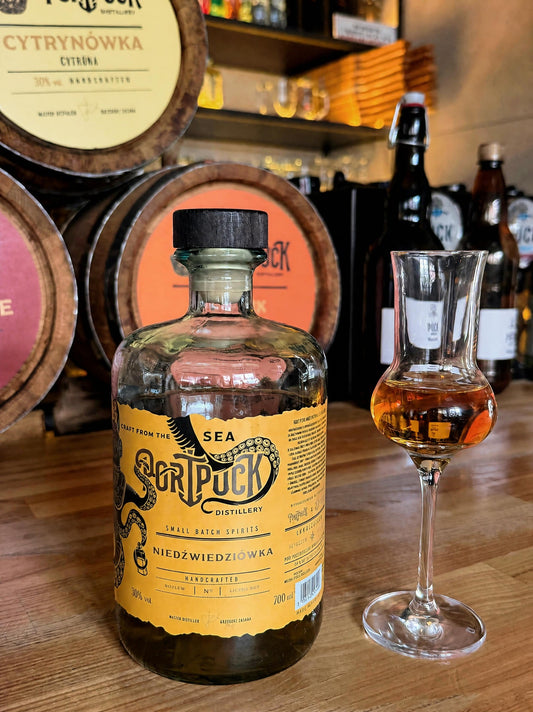 Butelka Niedźwiedziówki z Port Puck Distillery podana w kieliszkach na drewnianej desce